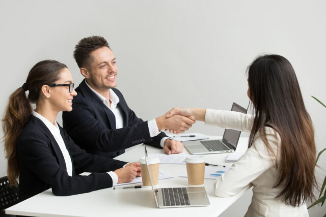 Best Human Resource Management System, Friendly satisfied partners handshaking at group meeting thanking for successful teamwork, smiling millennial businessman shaking hand greeting businesswoman, respect or making contract deal concept